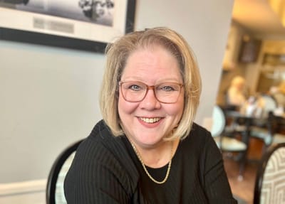 Smiling woman in a dining area with other people in the background