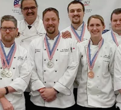 Chefs displaying medals at a culinary competition