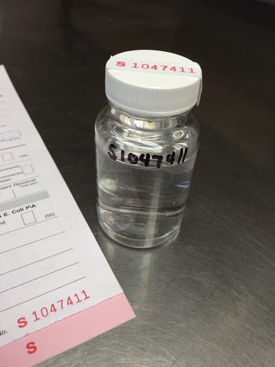 A clear bottle with a label and paperwork