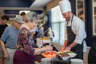 Resident interacting with a chef at a food service station