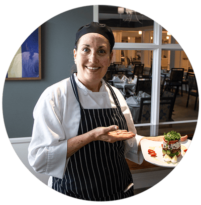 Chef presenting a beautifully plated dish in the dining area