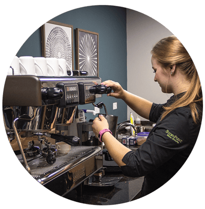 Staff member operating a coffee machine in a cafe setting
