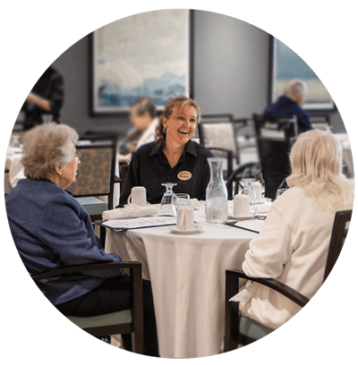 Residents enjoying a meal with a staff member in a dining area
