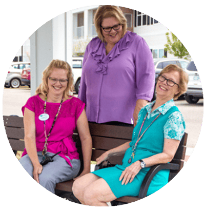 Three staff members laughing on a bench