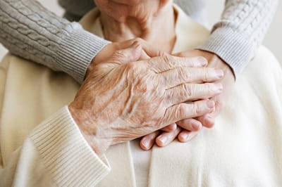 Close-up of an elderly person's hands with younger hands resting on top
