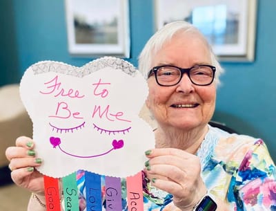 Resident holding a colorful sign in a common area