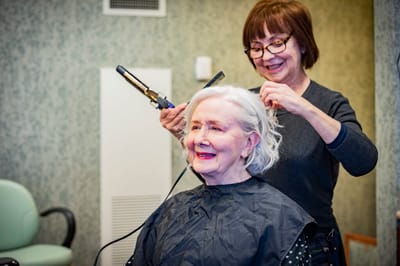 Resident receiving a hair styling service