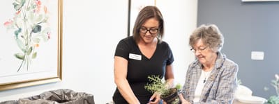 Staff member assisting resident with plant.