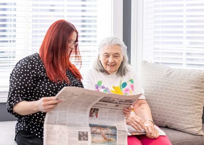 Staff member reading newspaper with resident