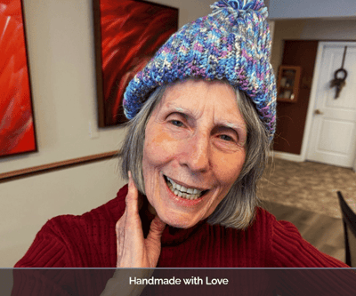 A smiling resident wearing a handmade hat