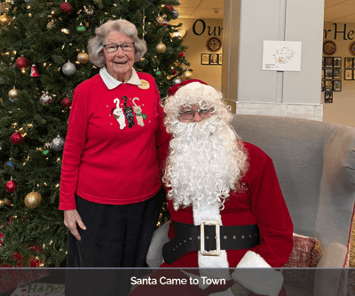 Resident posing with Santa in the lobby during a holiday event