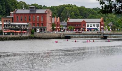 Exterior view of buildings near a waterway with rowers