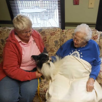 Resident enjoying time with a staff member and a dog
