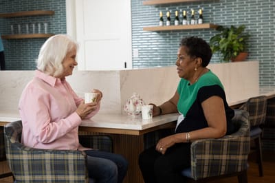 Two residents chatting over tea in a common area