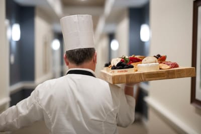 Chef carrying a platter of gourmet food in a corridor