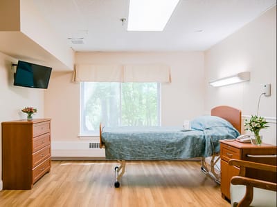 A cozy resident room with a bed and TV