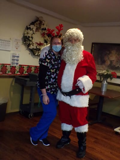 Staff member with Santa Claus at a holiday event
