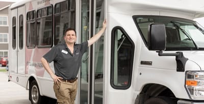 Staff member posing with facility transport vehicle