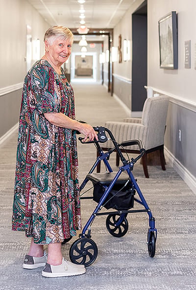 A resident walking with a walker in a hallway