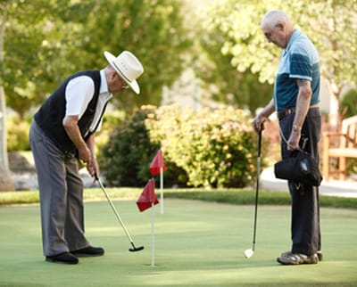 Two seniors playing golf on a putting green