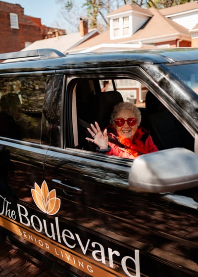 Senior resident waving from a facility van