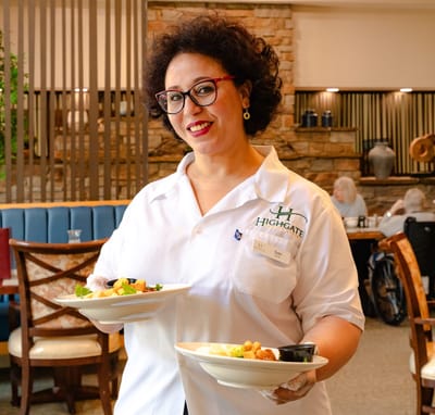 Staff member serving meals in the dining room