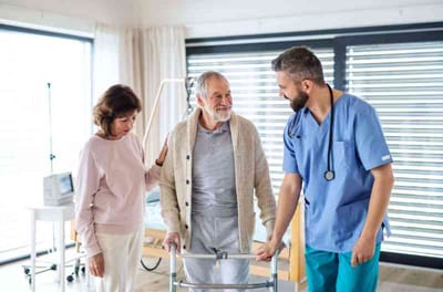 A caregiver assisting a resident with a walker in a bright room