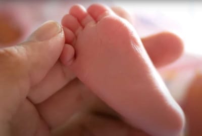 A close-up of a baby's foot being held