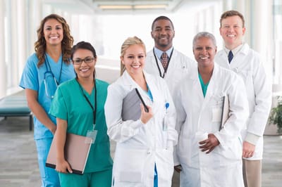 A diverse group of smiling healthcare professionals in a well-lit hallway