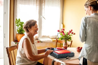 A smiling resident enjoying a meal in a bright dining area