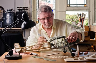 A resident building a model airplane in a sunlit room