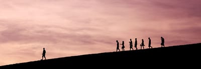 Silhouette of people walking against a sunset sky