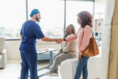 Healthcare professional shaking hands with guests in an interior setting