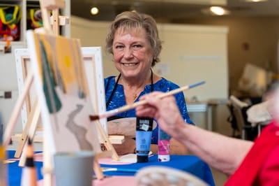Resident painting during an art activity in a bright room