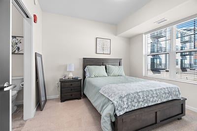 Cozy bedroom with a bed, nightstand, and bathroom visible
