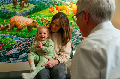 A woman holding a baby smiling at an older man