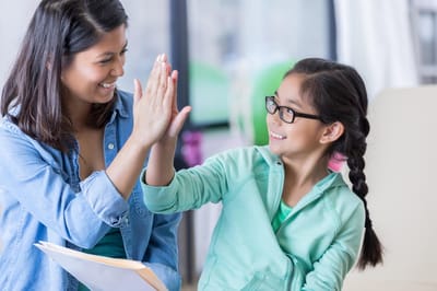 A woman and a girl giving a high-five indoors