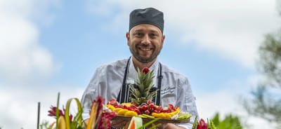 Chef presenting a colorful fruit platter in an outdoor setting