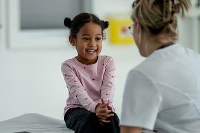 A young girl smiling with a healthcare professional.