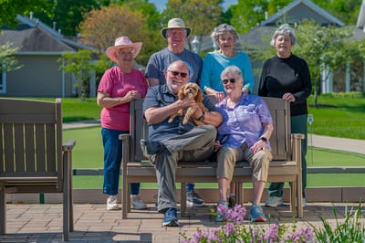 Residents and staff enjoying time outdoors with a small dog
