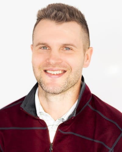 A smiling young man in a maroon jacket