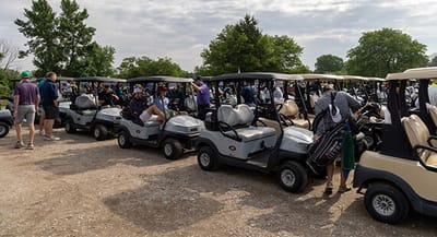Golf carts lined up at an outdoor event