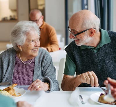 Residents enjoying a meal and conversation in the dining area