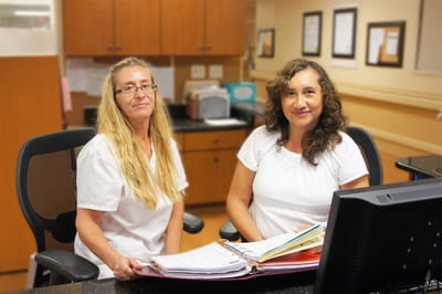 Two staff members at a reception desk smiling