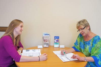 Two women discussing paperwork at a table