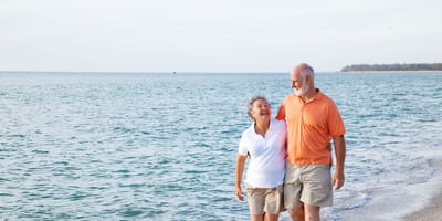 Couple walking on the beach by the water