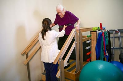 A caregiver assisting a resident on stairs during therapy