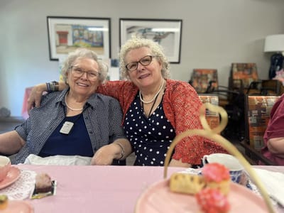 Two smiling women enjoying tea in a common area