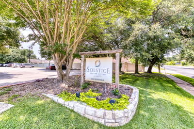 Sign for Solstice Senior Living at Austin surrounded by greenery