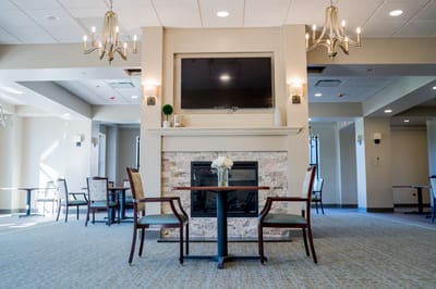 Common area with tables and chairs near a fireplace